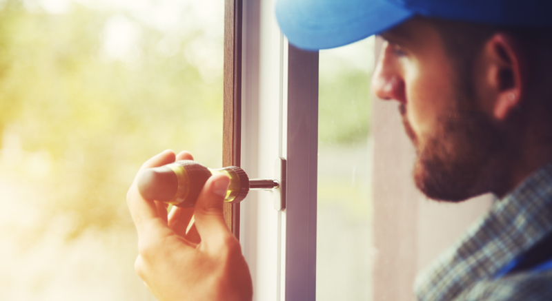 service man installing window with screwdriver